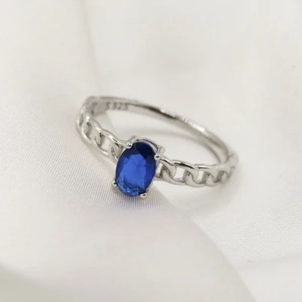 Anillo de plata con piedra oval azul, diseño elegante con montura calada que realza la piedra central. Diseño exclusivo de Mena Fine Jewelry.