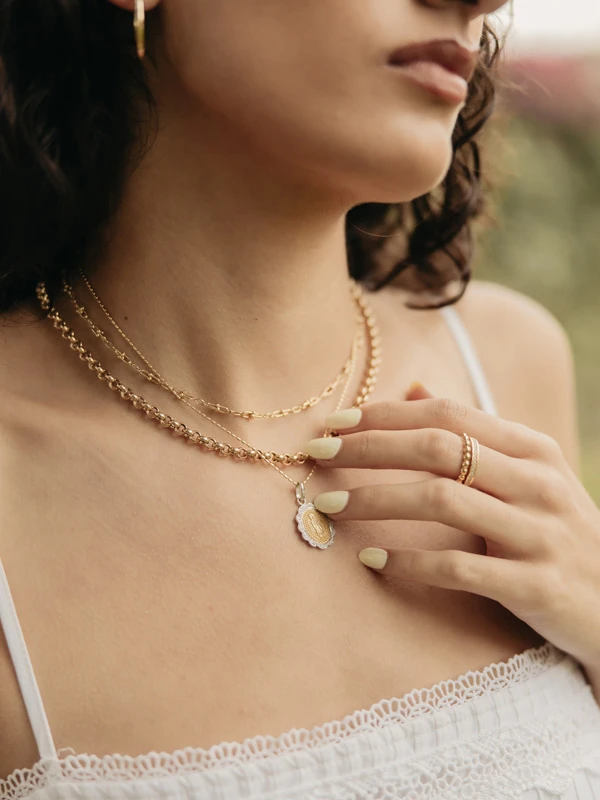 Primer plano del escote de una modelo luciendo collares y gargantillas de Mena Fine Jewelry.
