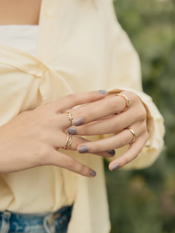 Primer plano de ambas manos de una modelo con anillos de diferentes modelos. Diseños exclusivos de Mena Fine Jewelry.
