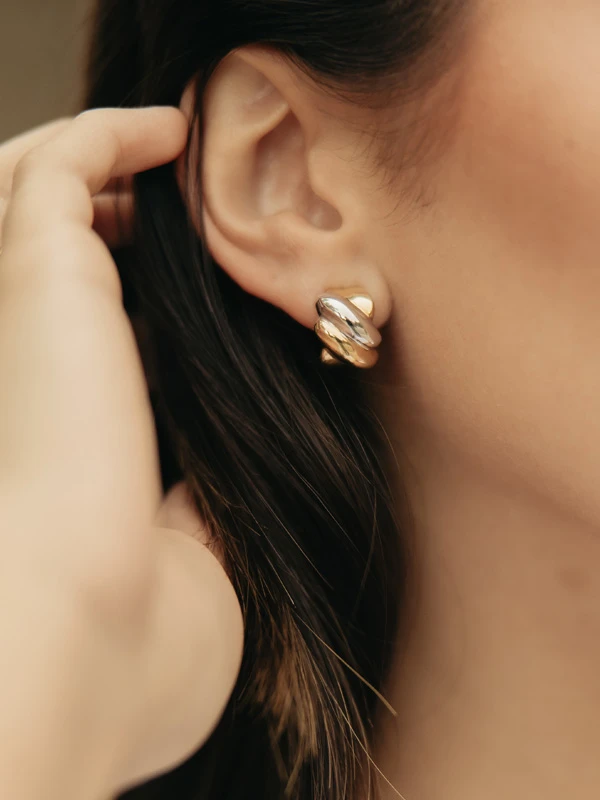 Primer plano de una modelo llevando unos aretes dorados de Mena Fine Jewelry.
