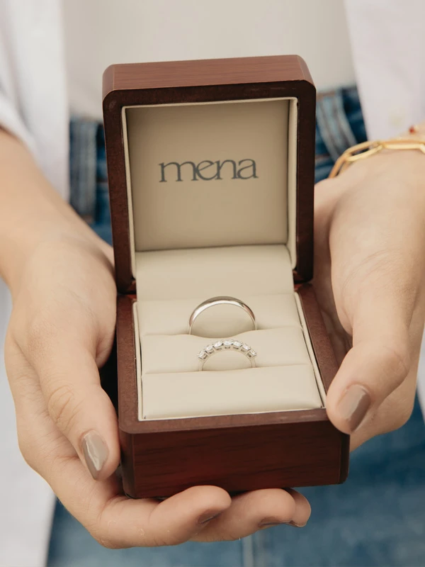 Mujer teniendo en sus manos una caja con anillos anillos de compromiso para marido y mujer. Diseños personalizados de Mena Fine Jewelry.