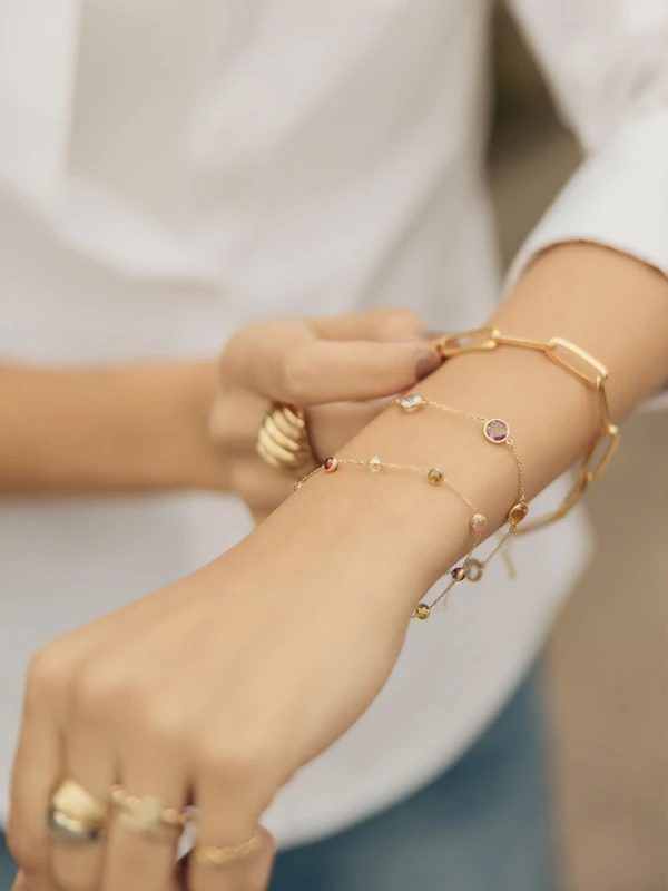 Modelo femenina luciendo diferentes modelos de pulseras doradas. Diseños exclusivos de Mena Fine Jewelry.